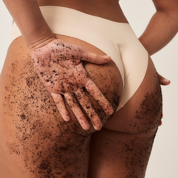 Model applying Original Coffee Scrub to her bum and the back of her thigh, from The Squat Drop Kit.